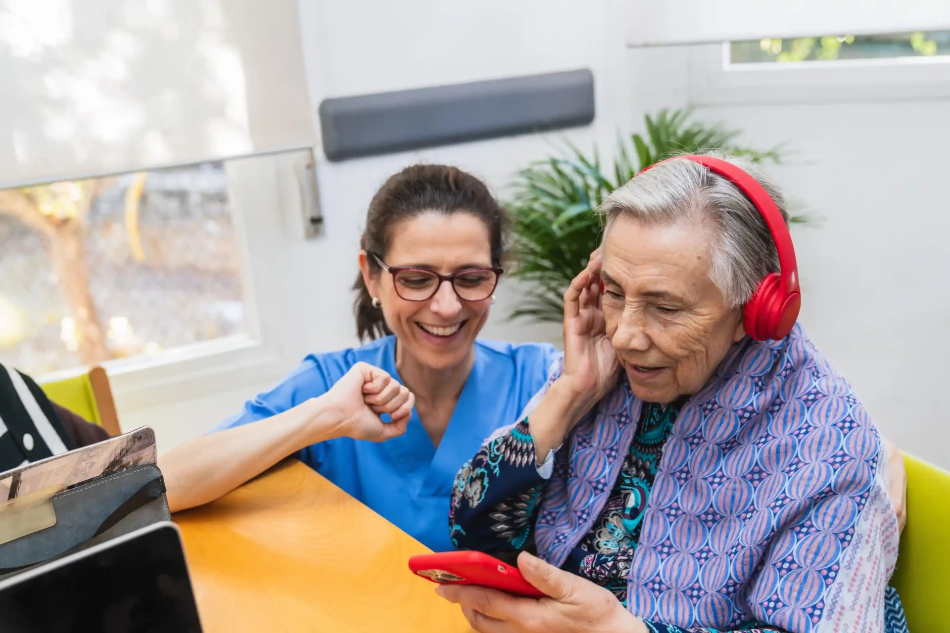 Nurse helping elderly woman use phone