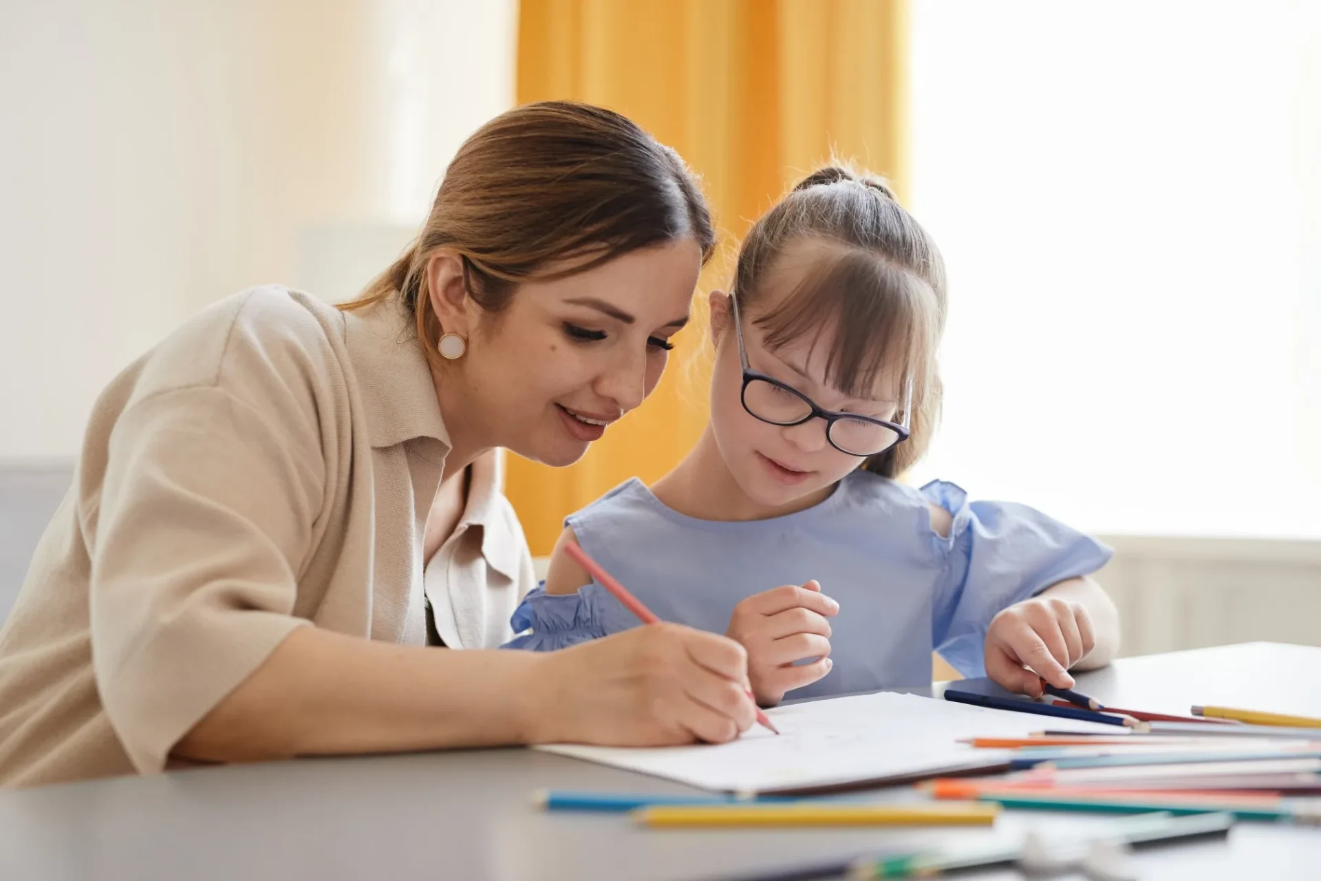 Support worker drawing with young girl with disability