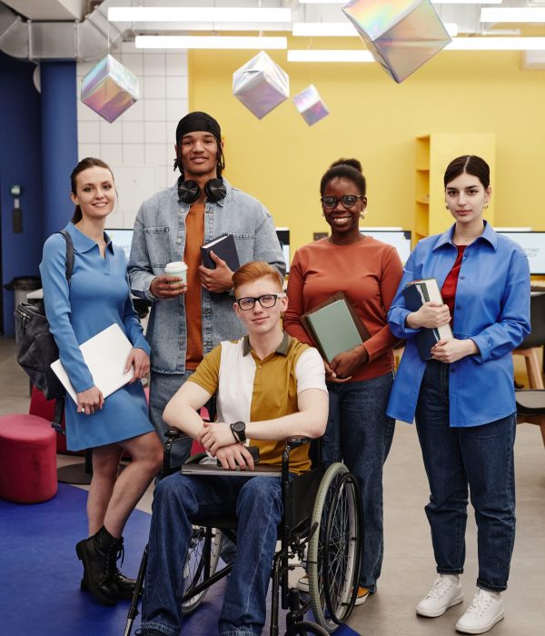 Vibrant full length portrait of diverse group of students young man with disability in foreground all looking at camera