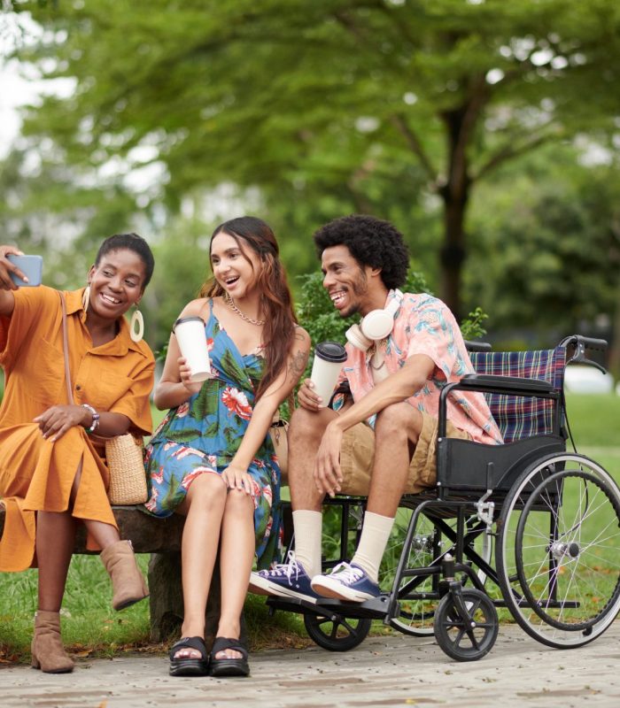 Group of joyful friends taking selfie in city park
